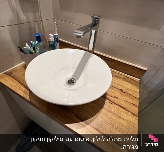 כיור עגול עם ברז על משטח עץ בחדר אמבטיה
